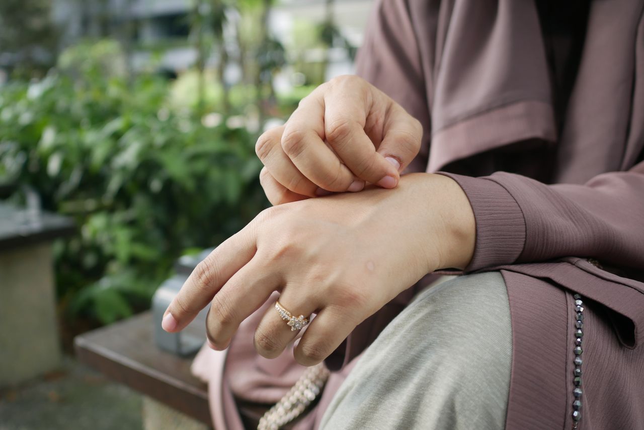 Close-up of hands with a beautiful ring in an outdoor setting, showcasing elegance.