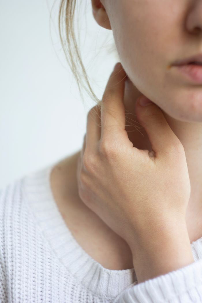 Intimate close-up of a woman's hand gently touching her neck, highlighting delicate skin texture.